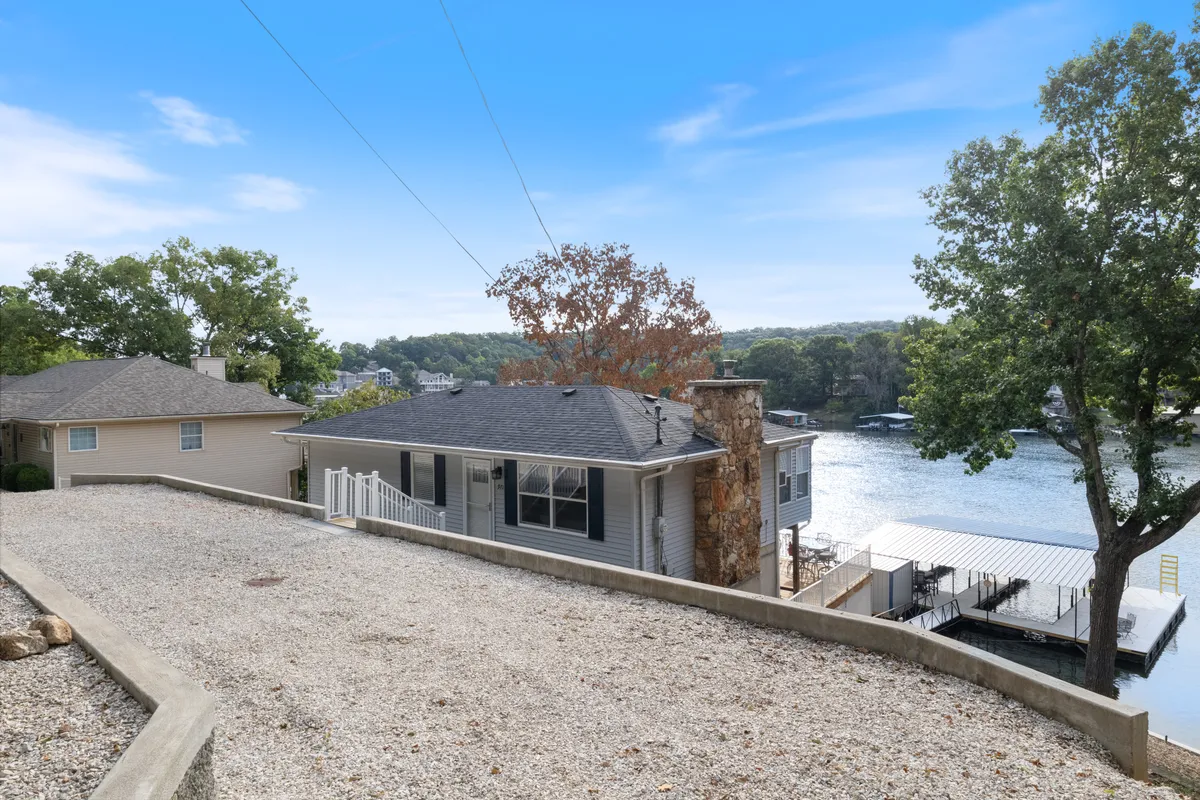 This exterior image captures the house, spacious dock, and the lake itself. The dock is clearly visible and appears inviting, offering direct access to the water for swimming, boating, or relaxing. The tranquil lake and well-maintained dock area highlight the primary features described in the section: private water access and lakeside fun.