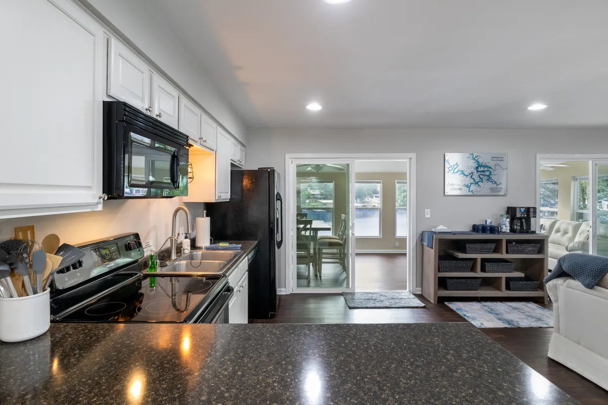 This image features a modern kitchen with a center island, sleek appliances, and expansive windows that frame views of the lake beyond. The natural light flooding in and the open layout create an inviting atmosphere for both cooking and socializing. Visible kitchen essentials reinforce the space’s readiness for culinary adventures.
