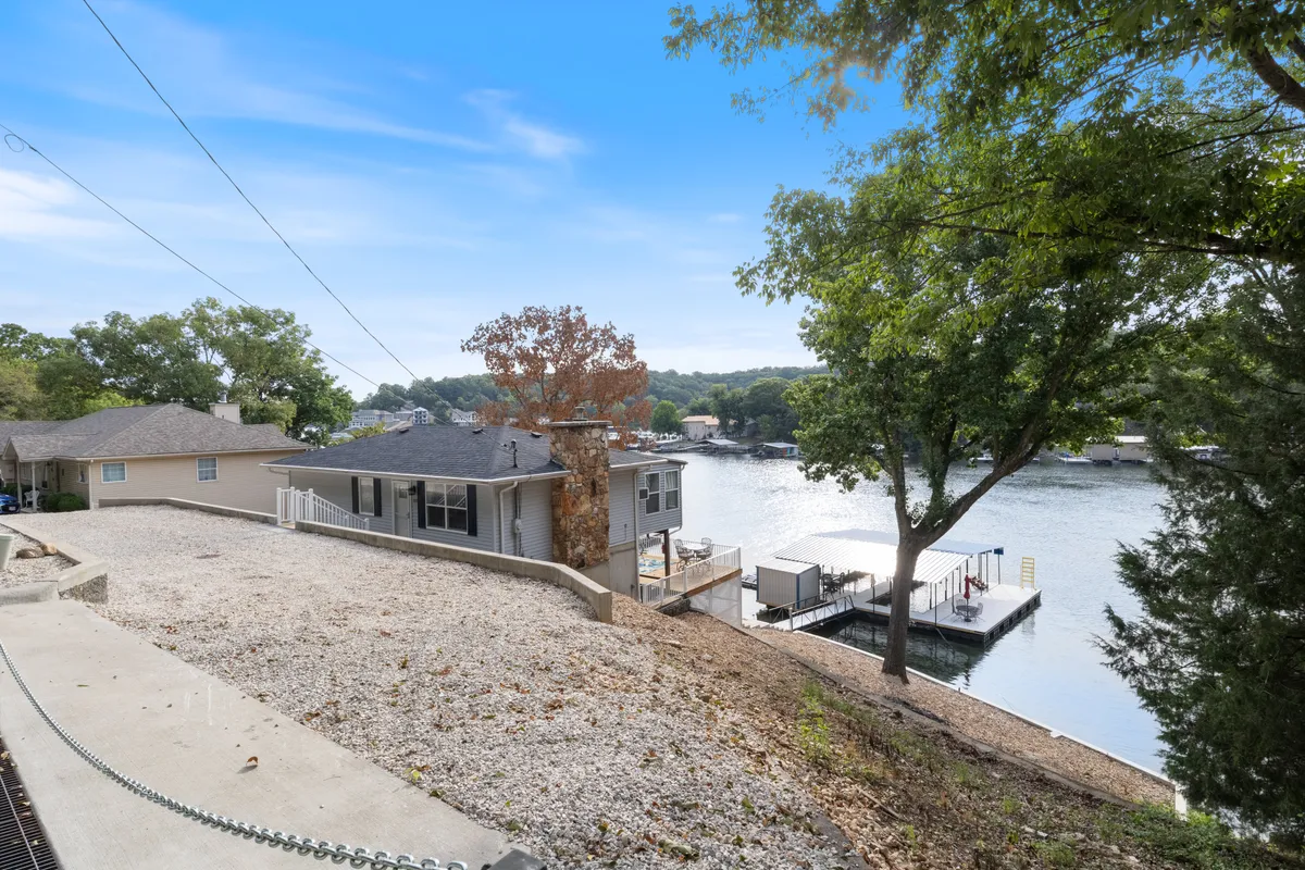 A serene lakeside scene featuring a house nestled among trees, with a docking area leading directly to the water. The calm lake view invites activities such as boating, fishing, or simply relaxing by the water’s edge, illustrating easy access to nature and outdoor adventures.